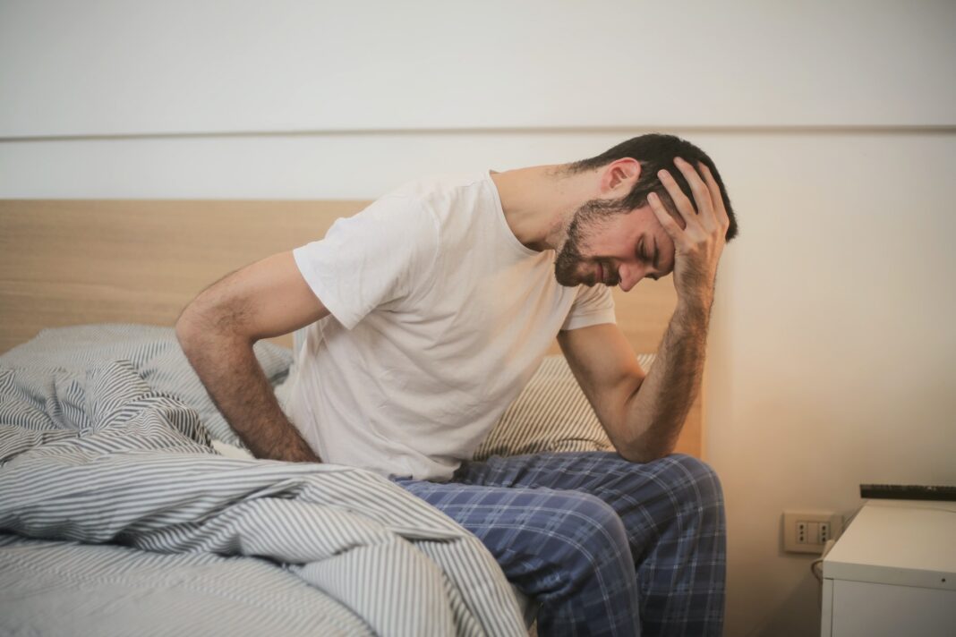 Nemocný muž sedí na posteli, infekce