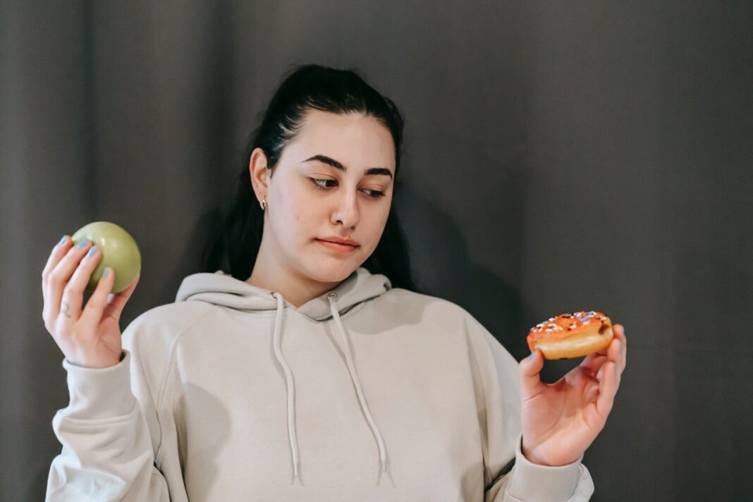 Žena váhá mezi jablkem a koláčem, poruchy výživy
